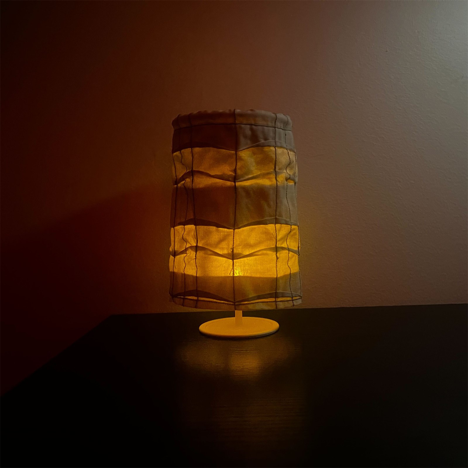 A quilted lamp glowing in a dark room