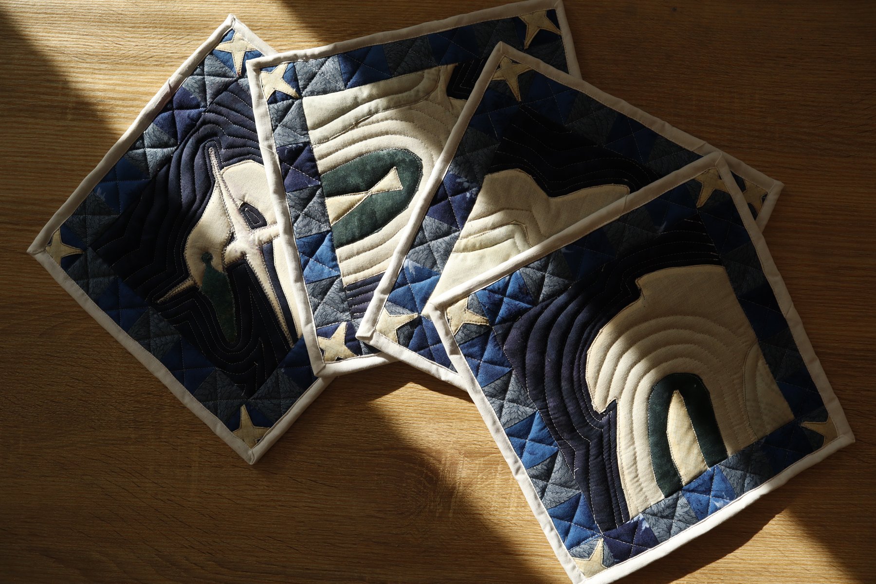 Four quilted swan potholders fanned out